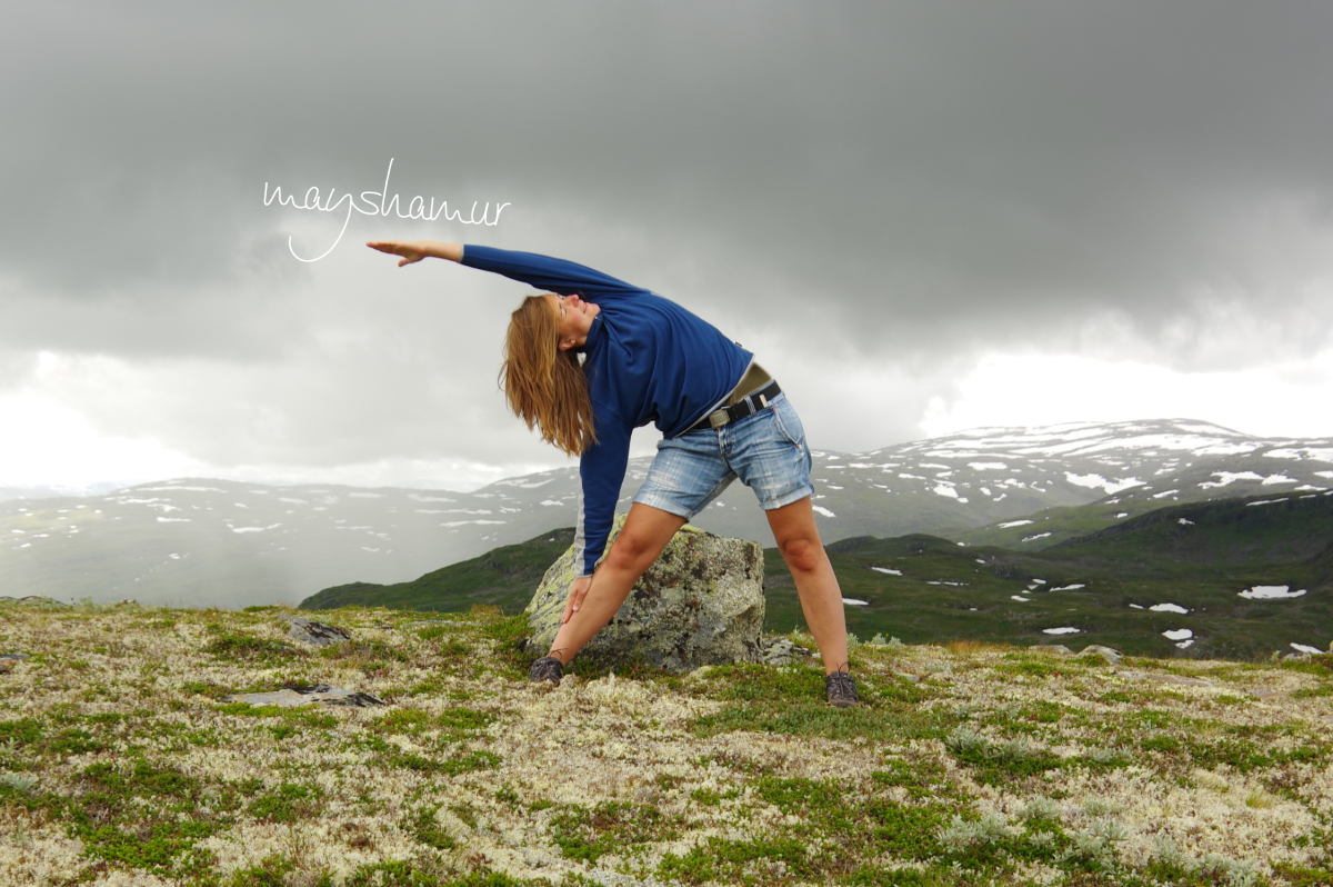Denise in der Asana (Yogastellung) Trikonasana auf einem moosbewachsenen Berg in Norwegen