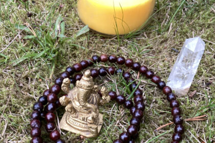 Ganesha-Murti mit Mala, einem Kristall und einer gelben Kerze auf Gras